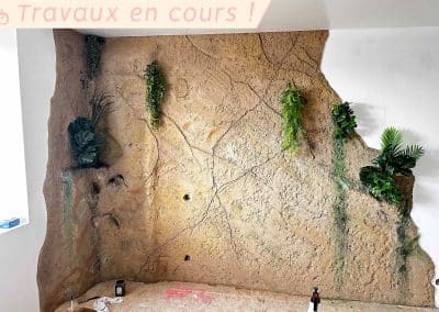 Décoration murale en imitation de roche verticale végétalisée.